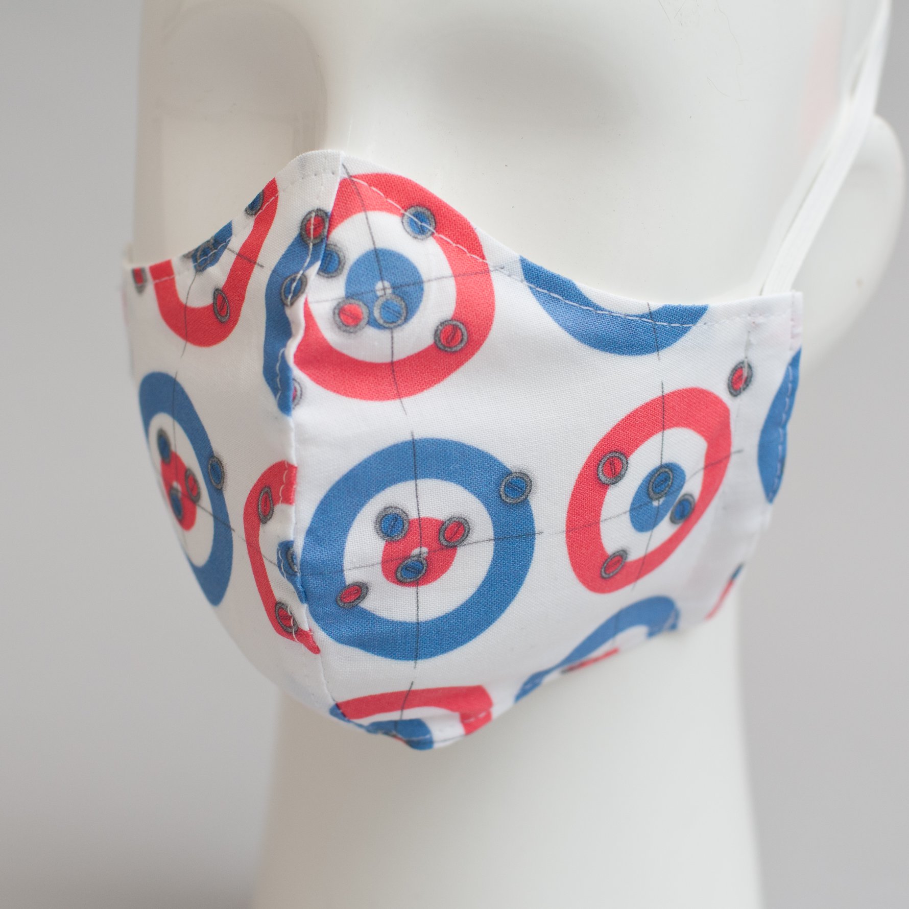 A white mannequin head wears a white mask with a curling house pattern in red and blue