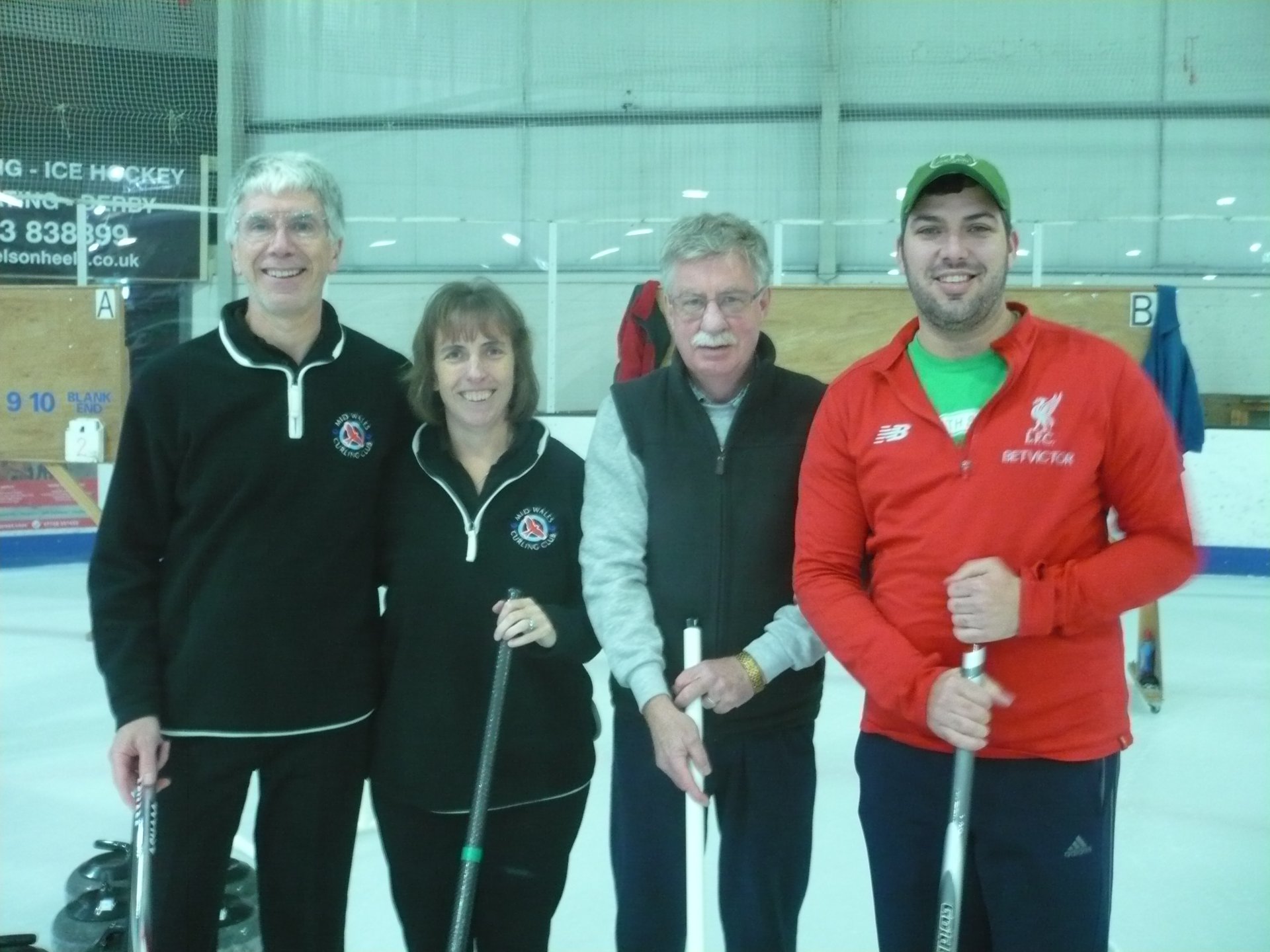 Photograph of Team Pougher, three white men and one white woman stood in a row on an ice rink,